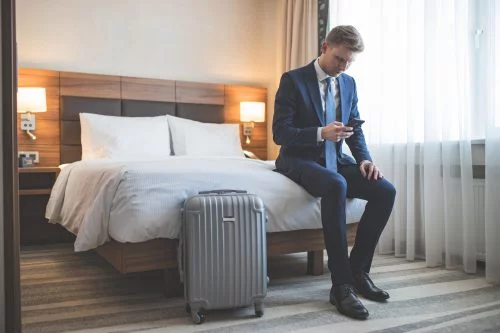 A man with a suitcase in a hotel checking his phone